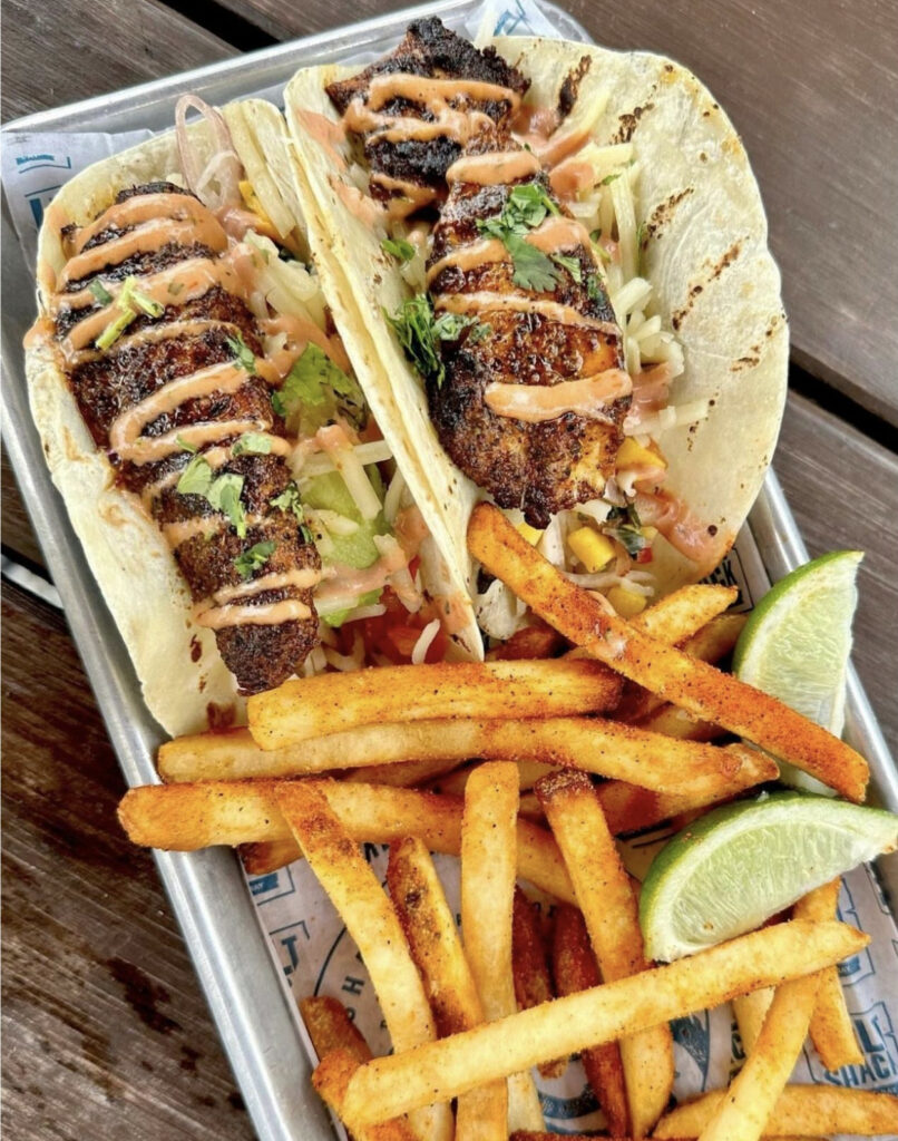 blackened mahi tacos with crispy french fries and lime wedges