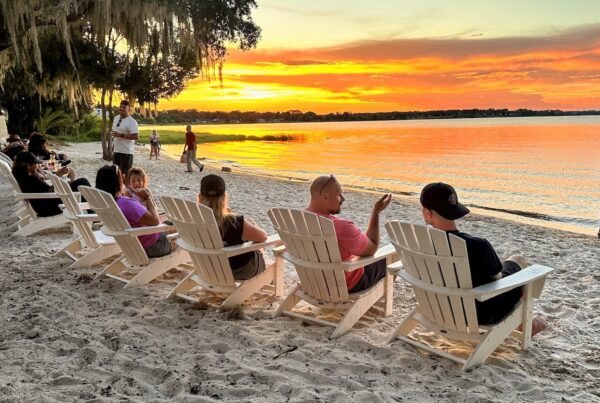 People sit in beach chairs overlooking a sunset over Lake Minneola